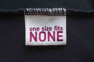 Close up Clothing label (fictional)   which  states that it won't fit anyone. Frustrating shopping for women with a larger size, most sizes won't fit. Statement against the one size fits all fairytale