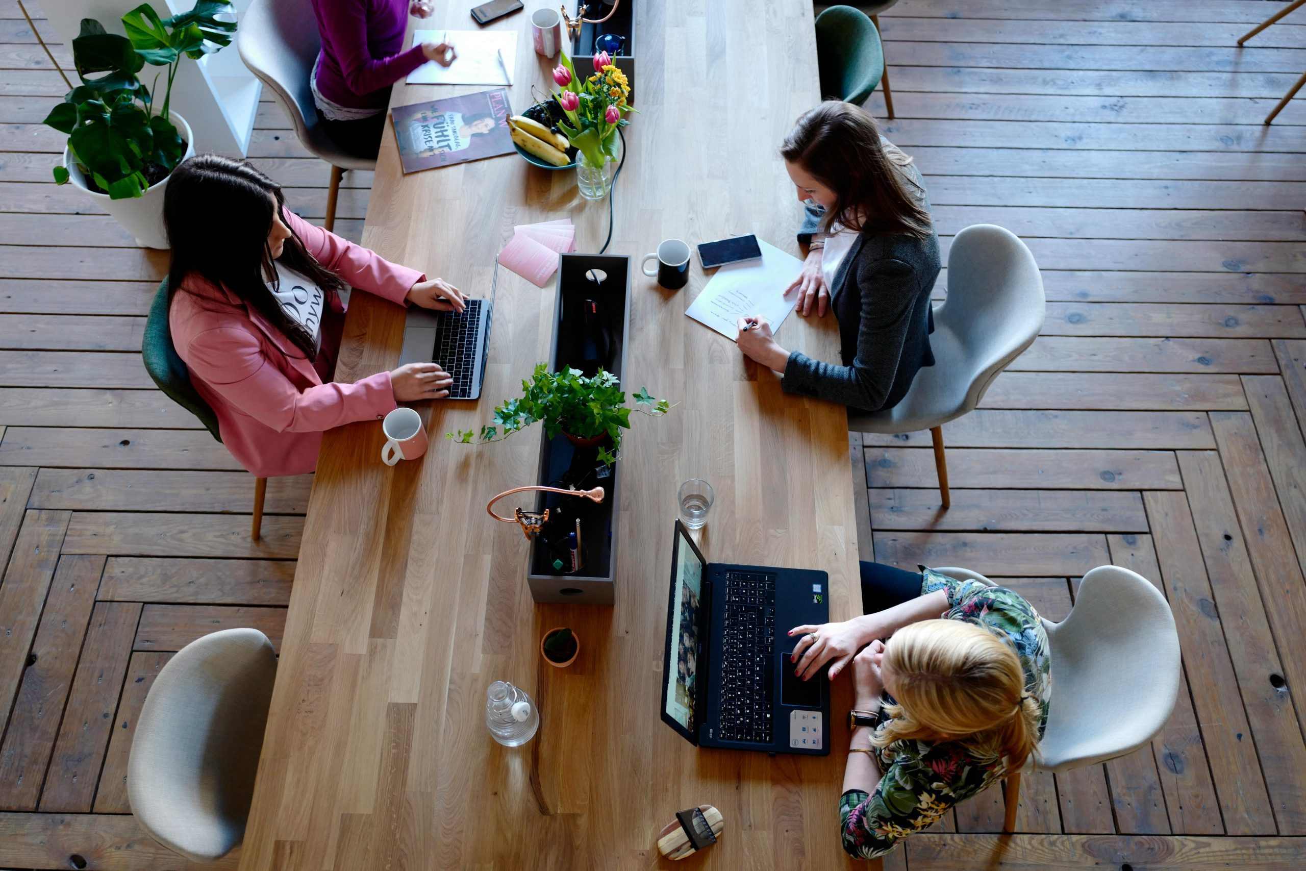 Three people working on a table typing on their laptops.