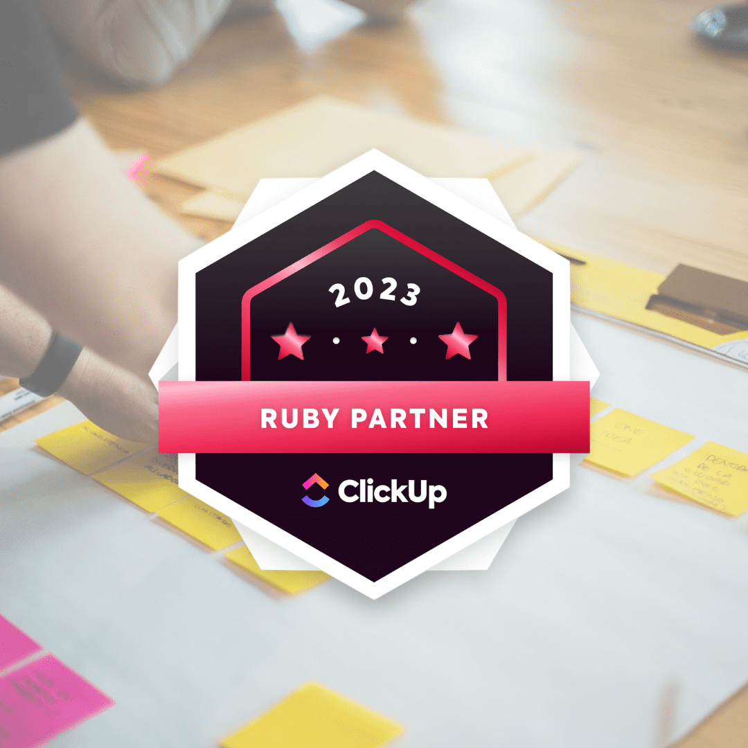A photo of someone putting sticky notes on a table overlayed with the ClickUp 2023 Ruby Partner badge.