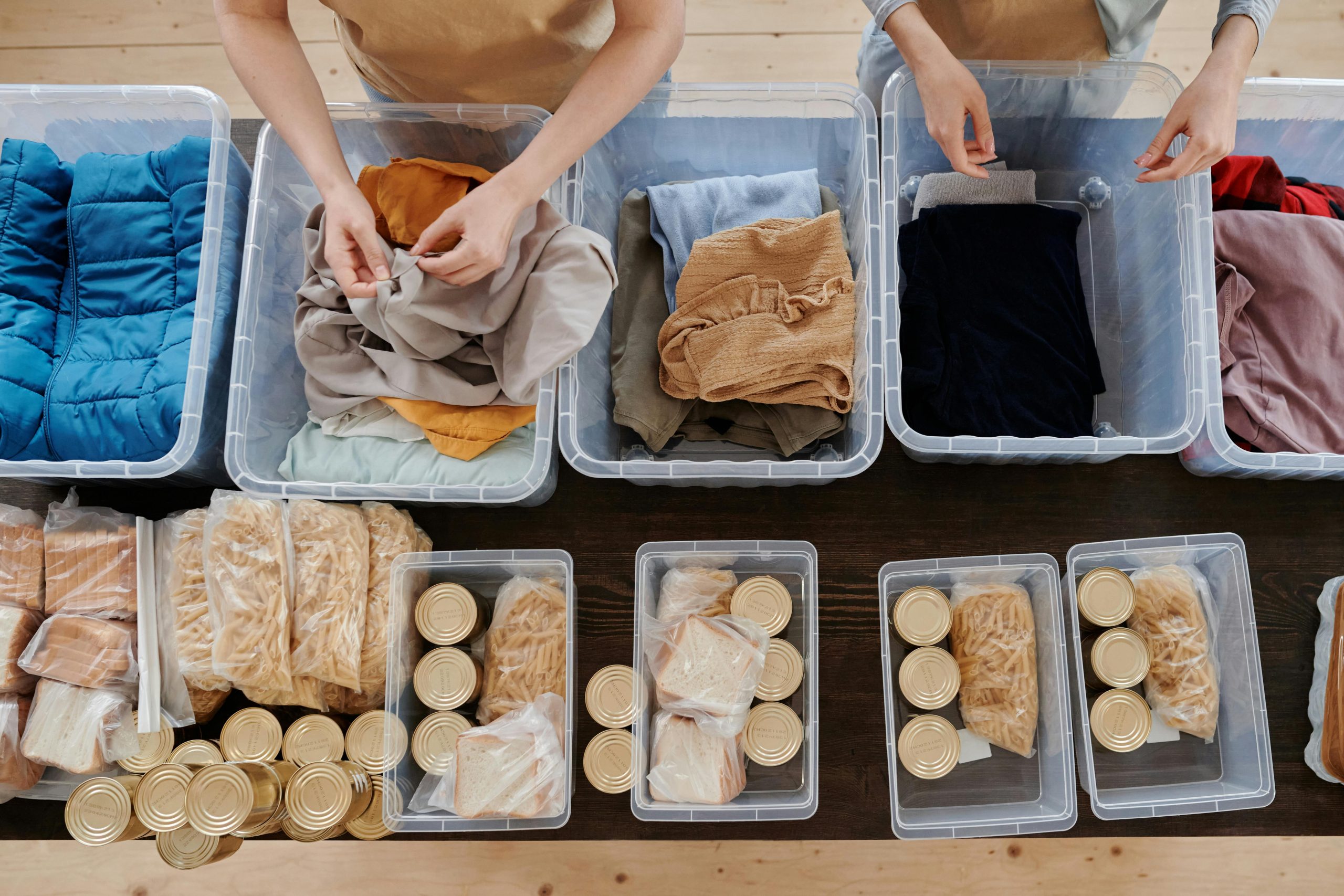 People packing plastic cartons full of food and clothing.